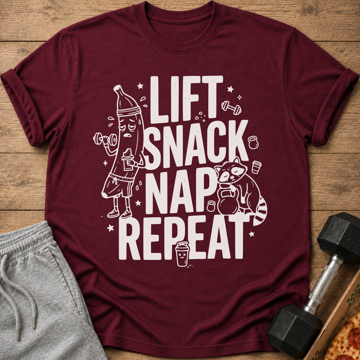 Maroon t-shirt with white text "LIFT SNACK NAP REPEAT" and cartoon illustrations.