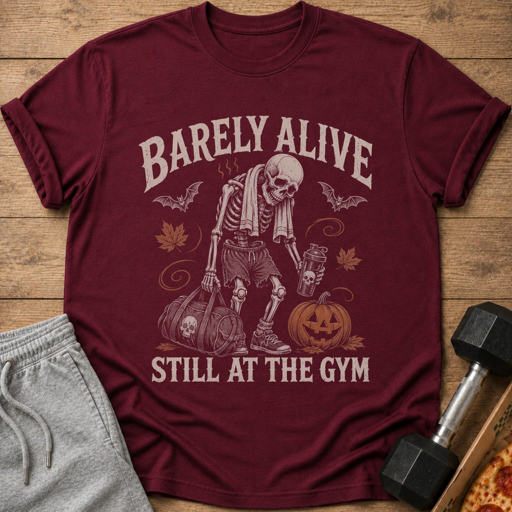 Maroon t-shirt with skeleton, gym bag, pumpkin, and text "Barely Alive Still at the Gym".