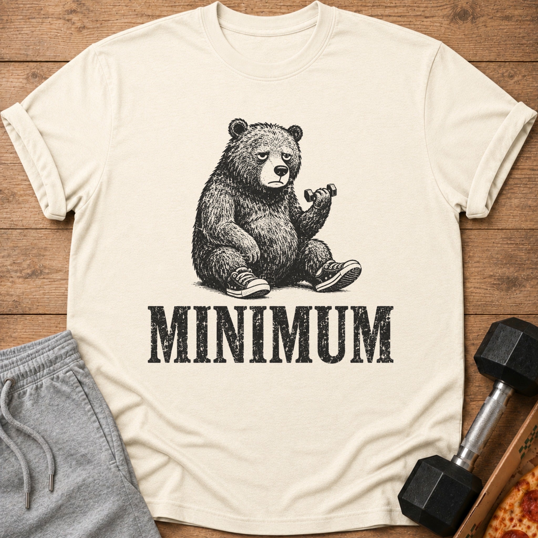 Cream t-shirt with graphic of tired bear lifting dumbbell and text "MINIMUM".