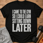 Black t-shirt with white text that reads "I came to the gym so I could earn sitting down later".