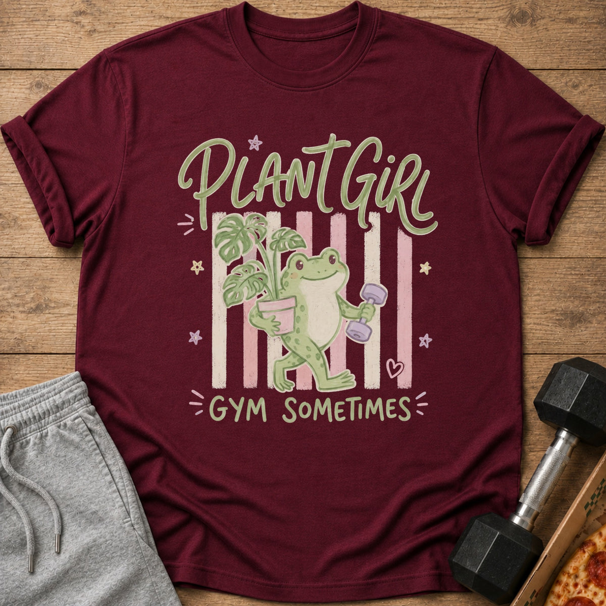 Maroon t-shirt with "Plant Girl Gym Sometimes" text and a frog holding a plant and dumbbell.
