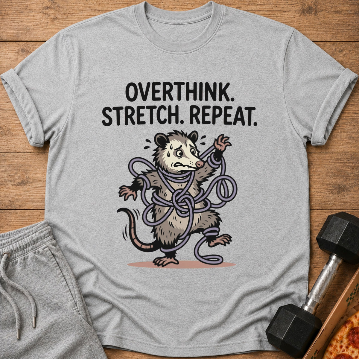 Gray t-shirt with text "OVERTHINK. STRETCH. REPEAT." and a cartoon possum tangled in purple ropes.