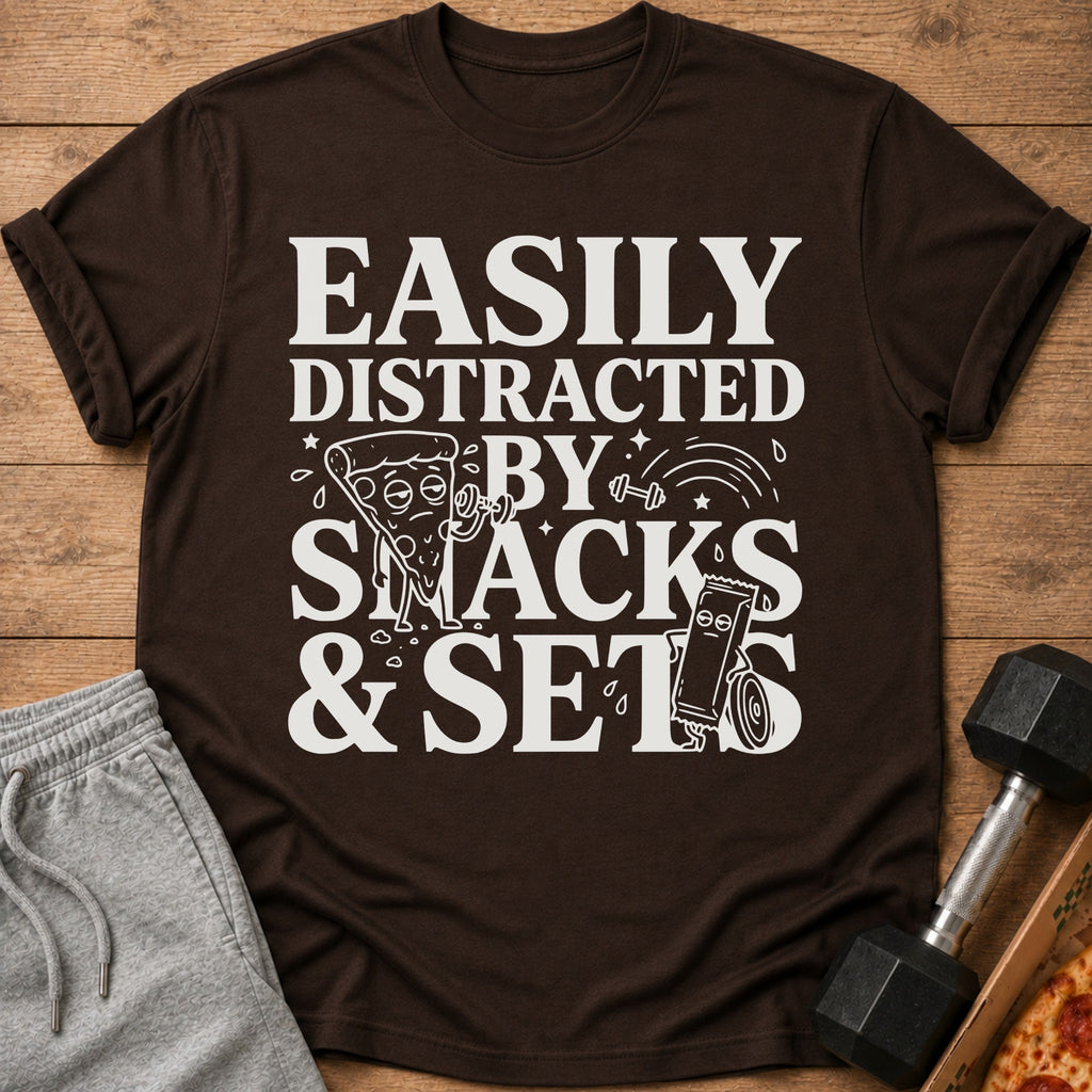 Brown t-shirt with "Easily Distracted By Snacks & Sets" text and illustrations.