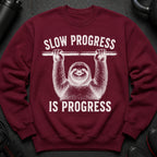 Maroon sweatshirt with graphic of a sloth holding a barbell and the text "SLOW PROGRESS IS PROGRESS".