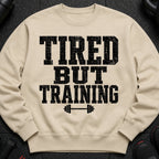 Light beige sweatshirt with "TIRED BUT TRAINING" text and barbell graphic.