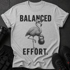 Grey t-shirt with black graphic of flamingo wearing sunglasses holding kettlebell and text "BALANCED EFFORT."