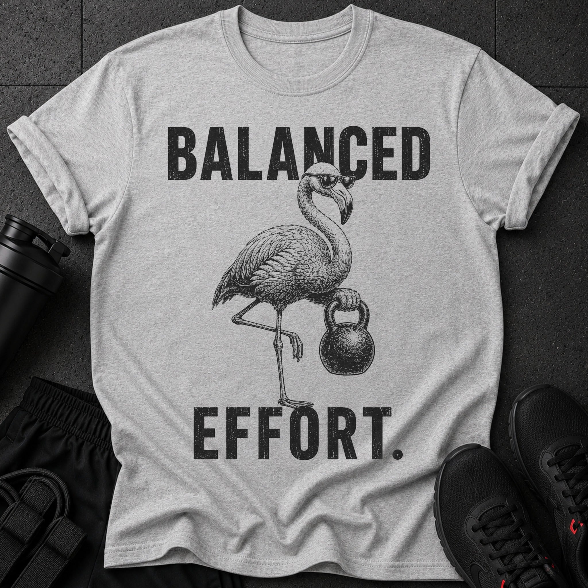 Grey t-shirt with black graphic of flamingo wearing sunglasses holding kettlebell and text "BALANCED EFFORT."