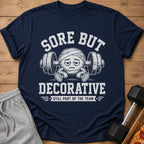 Navy t-shirt with "Sore But Decorative" and a bandaged ball on barbell.