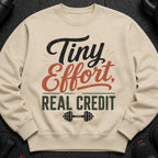 Light beige sweatshirt with "Tiny Effort, Real Credit" text and dumbbell graphic.