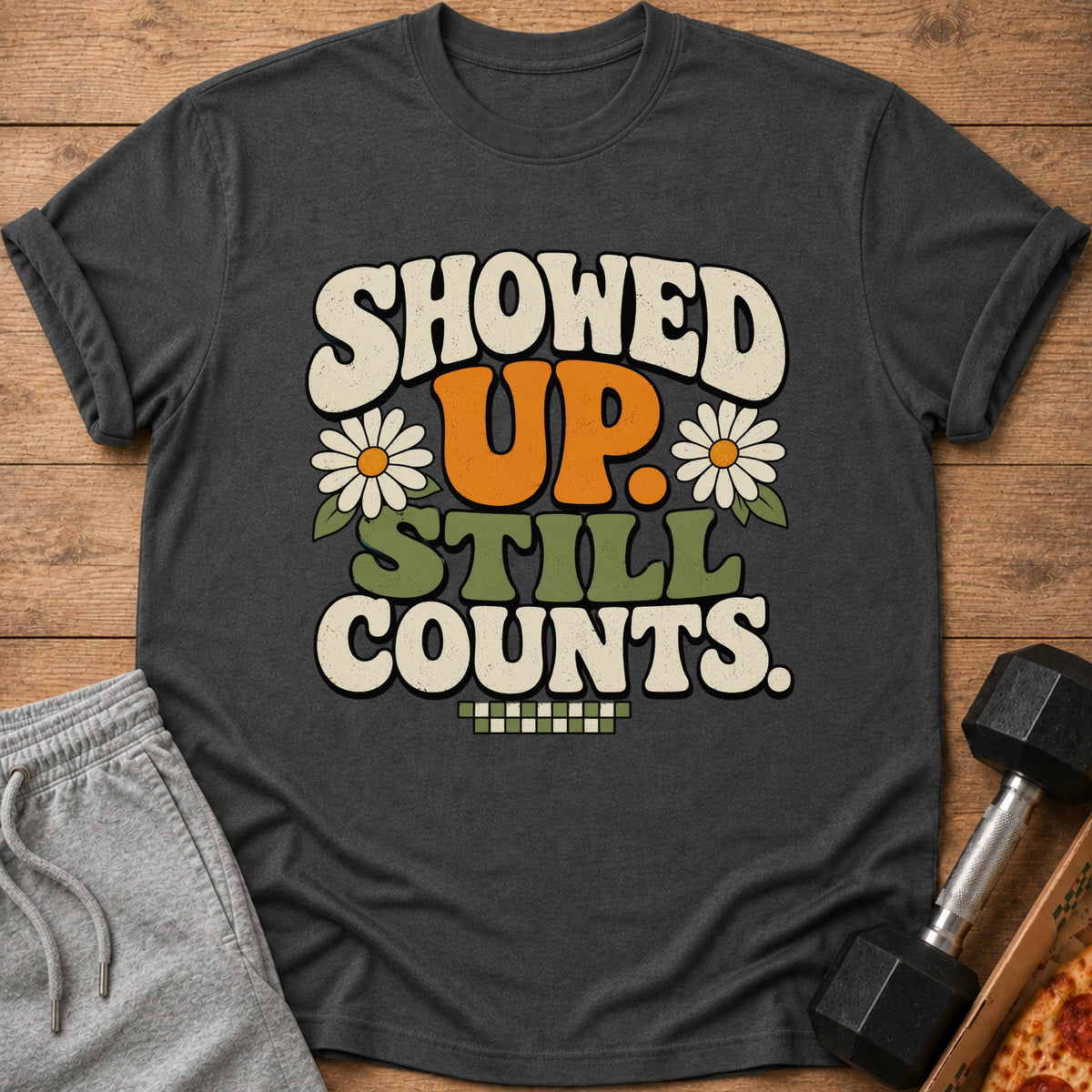 Dark t-shirt with retro graphic "SHOWED UP. STILL COUNTS." and daisies.
