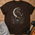 Brown t-shirt with crow on kettlebell and crescent moon graphic.