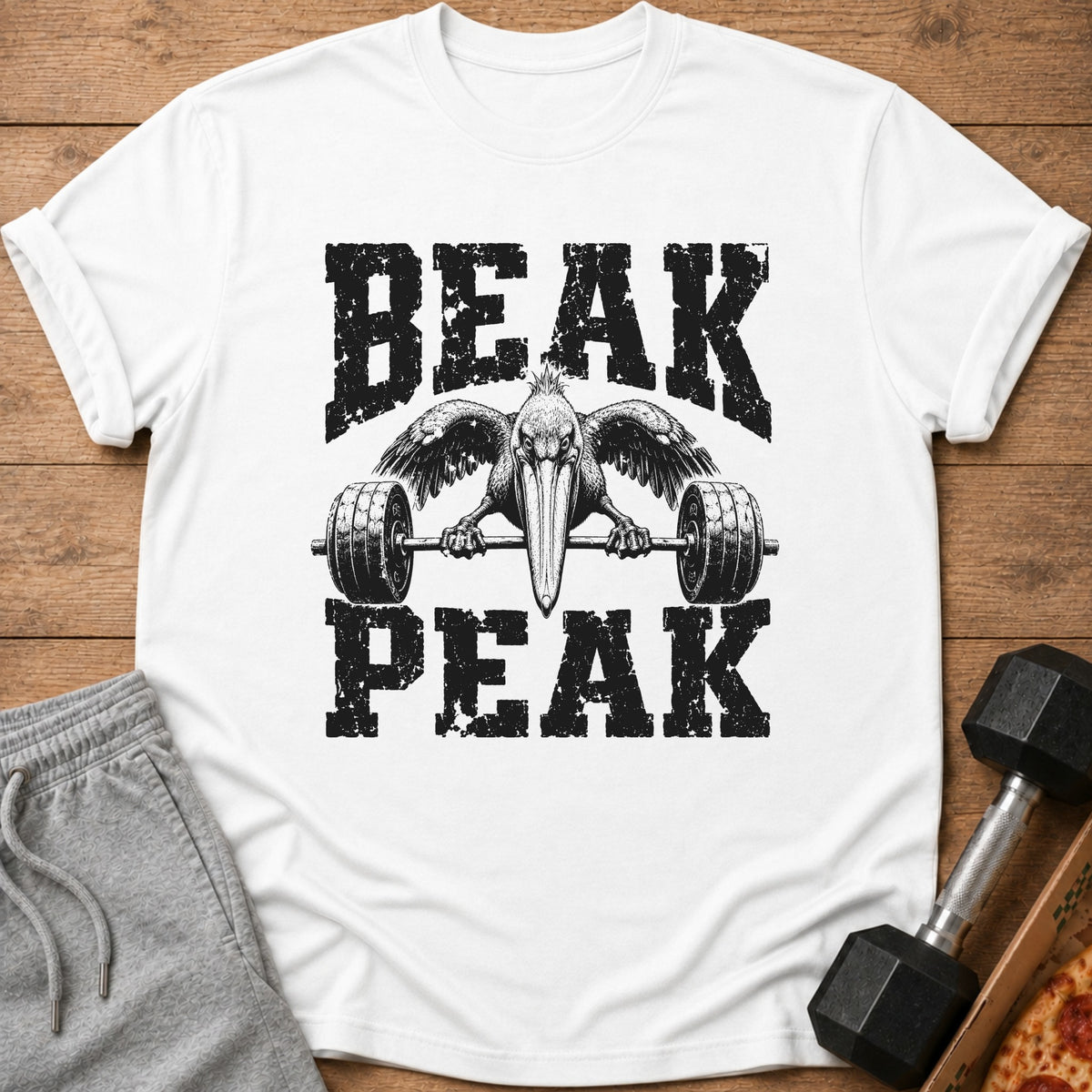 White t-shirt with black distressed graphic of a pelican lifting a barbell, text BEAK PEAK.