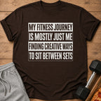 Dark brown t-shirt with "My fitness journey is mostly just me finding creative ways to sit between sets" text.