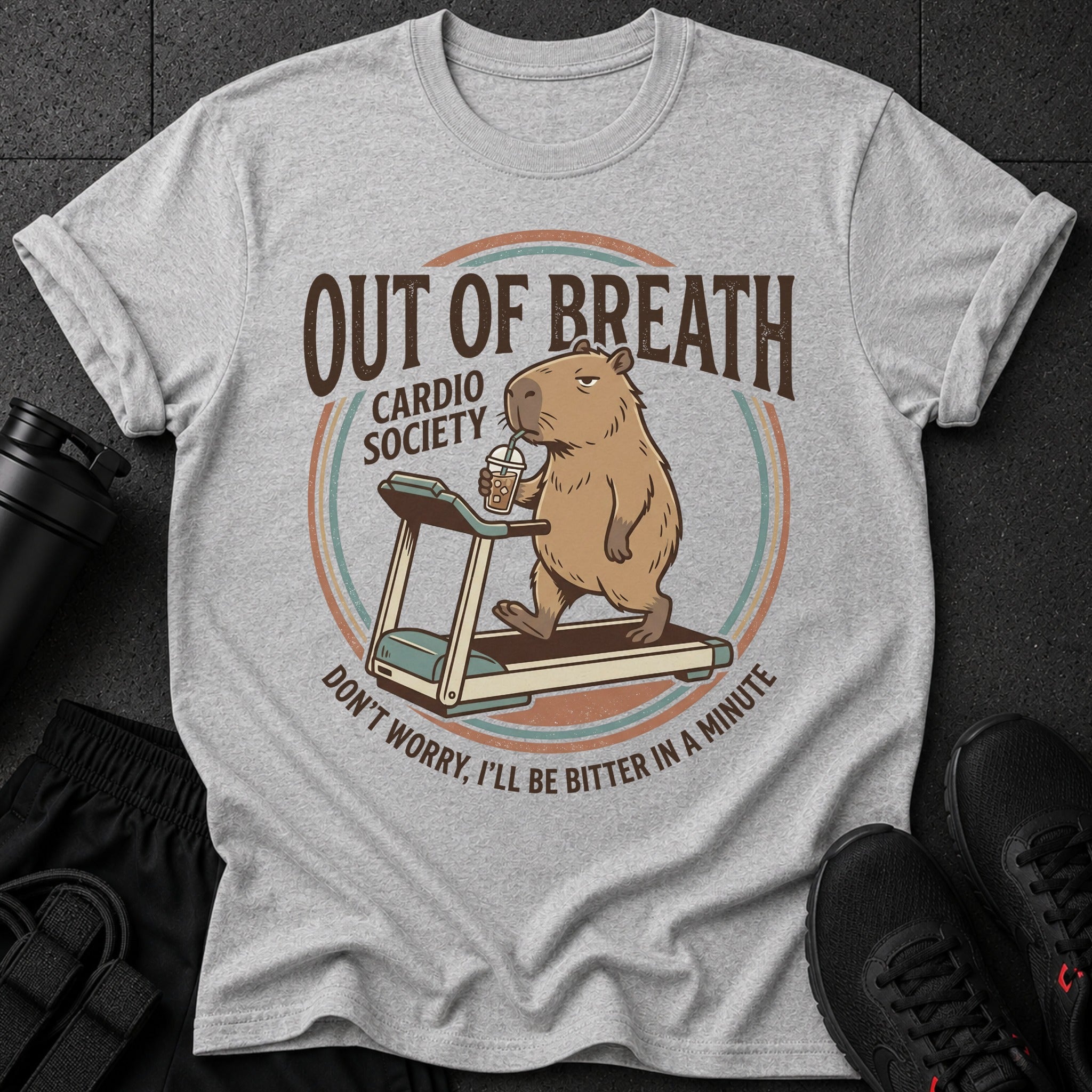 Gray t-shirt with cartoon capybara on treadmill, text "OUT OF BREATH CARDIO SOCIETY DON'T WORRY, I'LL BE BITTER IN A MINUTE."