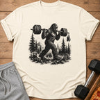 Bigfoot lifting weights with mountains and pine trees in the background.