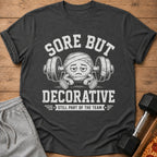 Dark grey t-shirt with "Sore But Decorative" text and injured emoji lifting weights.