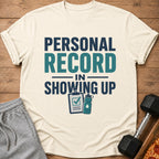 T-shirt with "Personal Record in Showing Up" text and fitness icons.