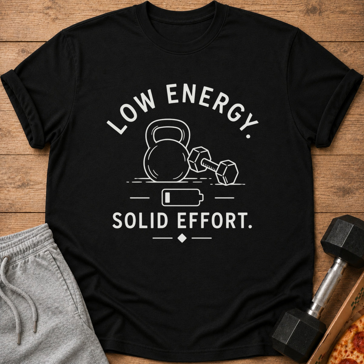 Black t-shirt with white text and graphics of gym equipment and a low battery symbol.