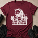T-shirt with a graphic of a sad raccoon lifting weights and the text "LOW ENERGY. HIGH EFFORT."