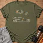 Green t-shirt with a line drawing of a person planking, connected to a couch and remote.