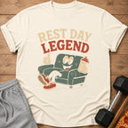 Cream t-shirt with "Rest Day Legend" text and cartoon of person on couch with shaker bottle.
