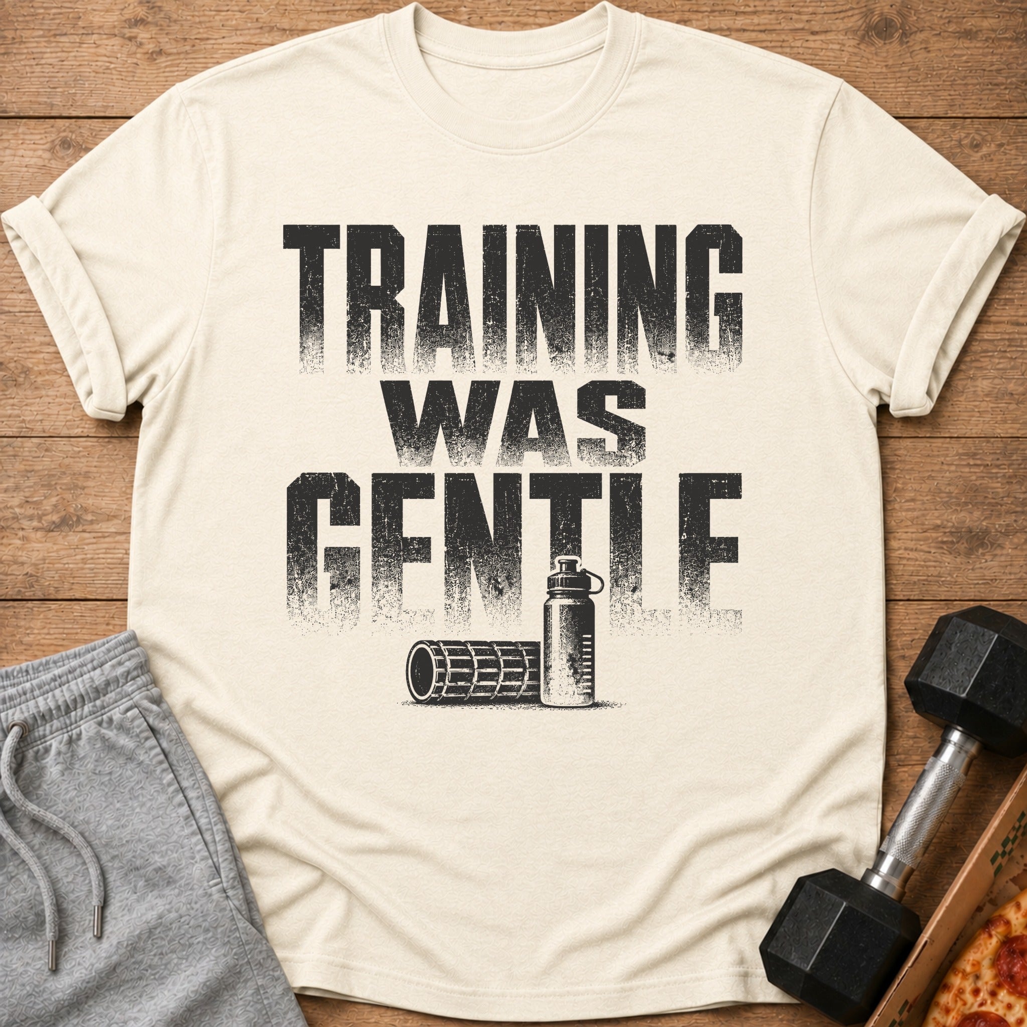 Cream t-shirt with "TRAINING WAS GENTLE" text, water bottle, and foam roller graphic.