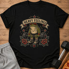 Black t-shirt with a cartoon frog weightlifter and "Heavy Feelings" banner.