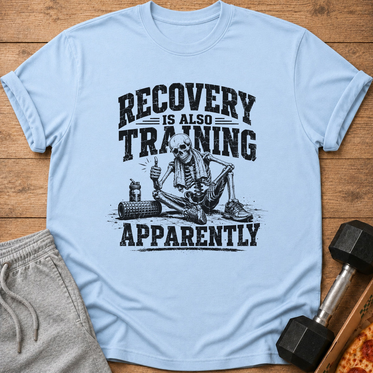 Light blue t-shirt with skeleton graphic and "RECOVERY IS ALSO TRAINING APPARENTLY" text.