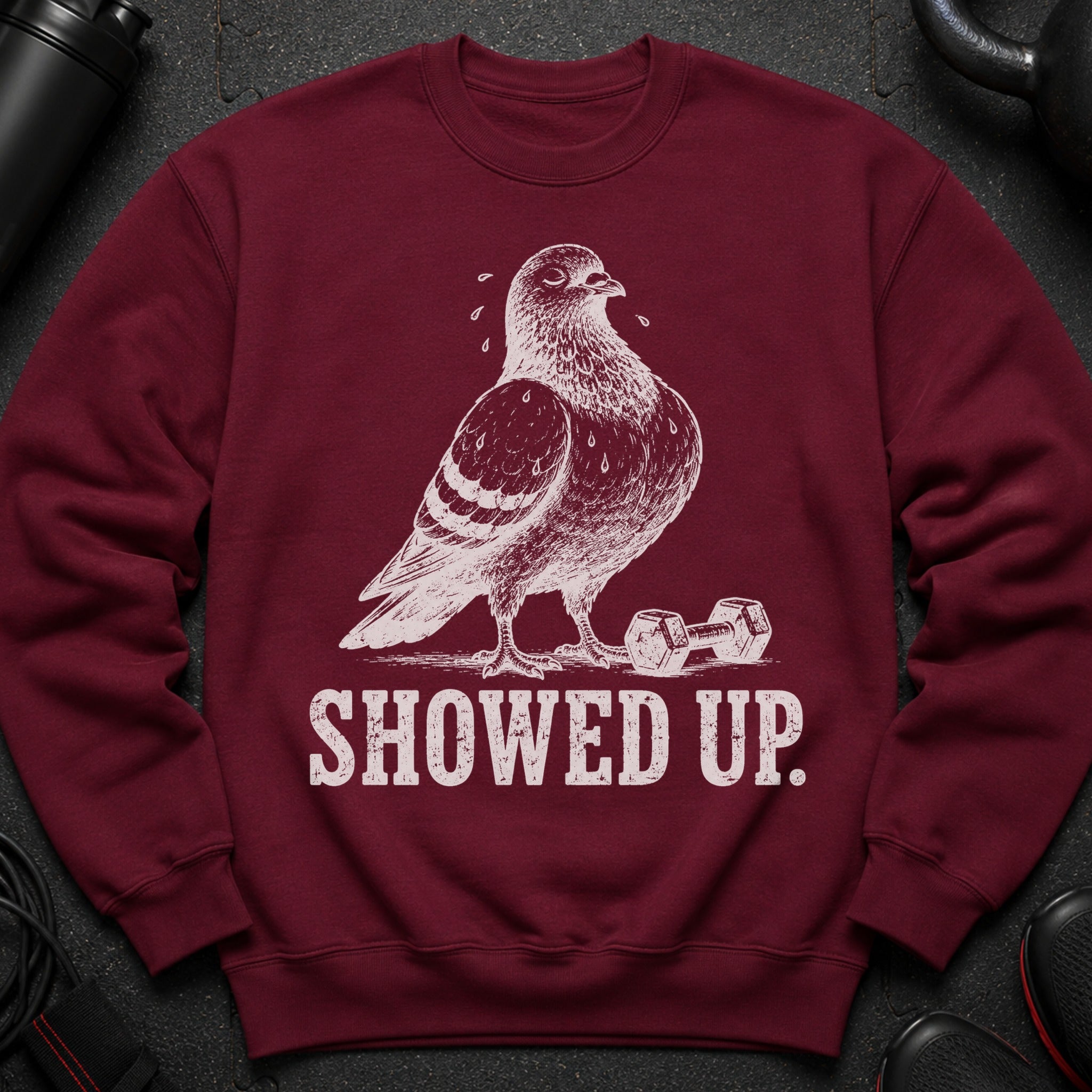 Maroon sweatshirt with a white sketched pigeon and dumbbell, and "SHOWED UP." text.