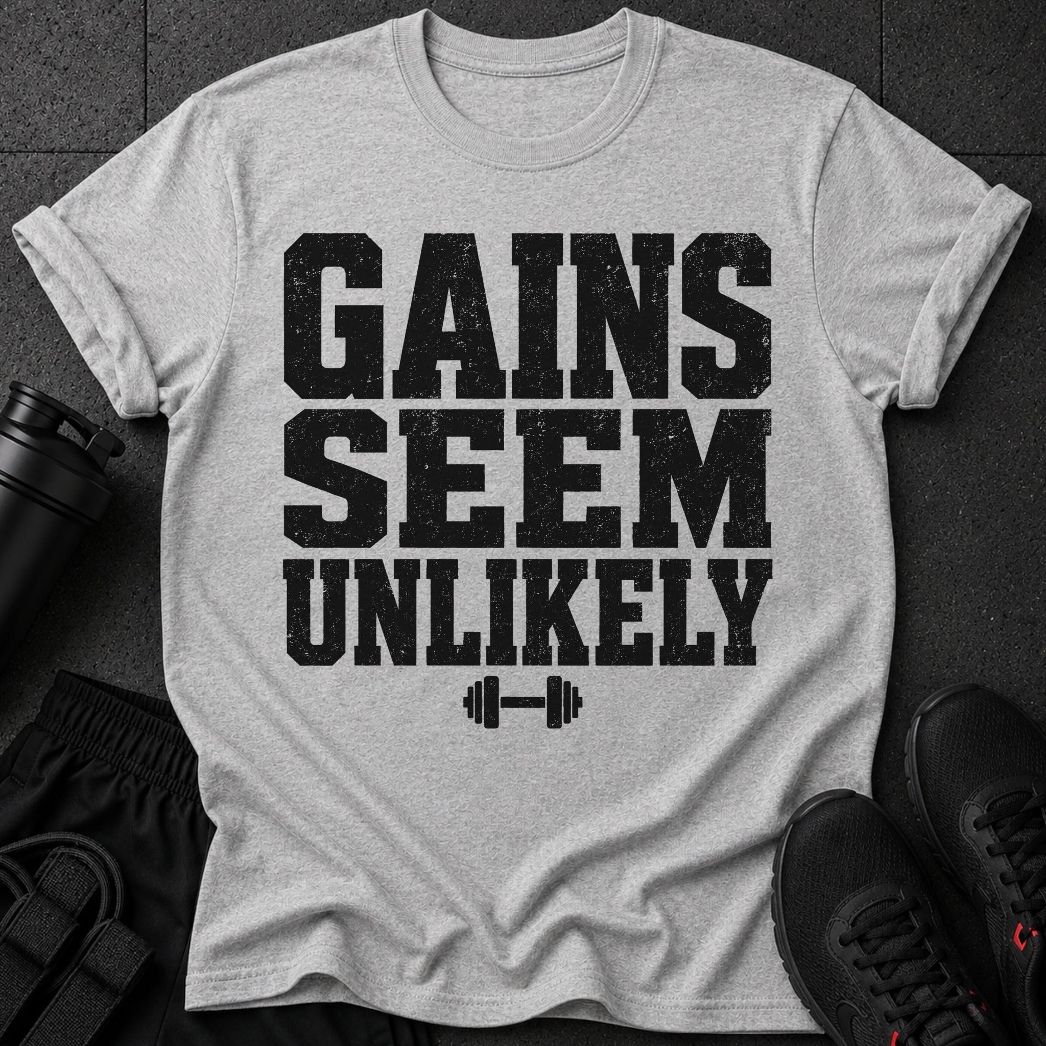 Grey t-shirt with black text that reads "GAINS SEEM UNLIKELY" and a dumbbell icon.