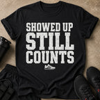 Black t-shirt with distressed white text "SHOWED UP STILL COUNTS" and a sneaker graphic.