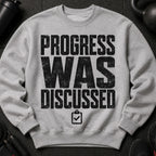 Grey sweatshirt with black distressed text "PROGRESS WAS DISCUSSED" and a checklist icon.