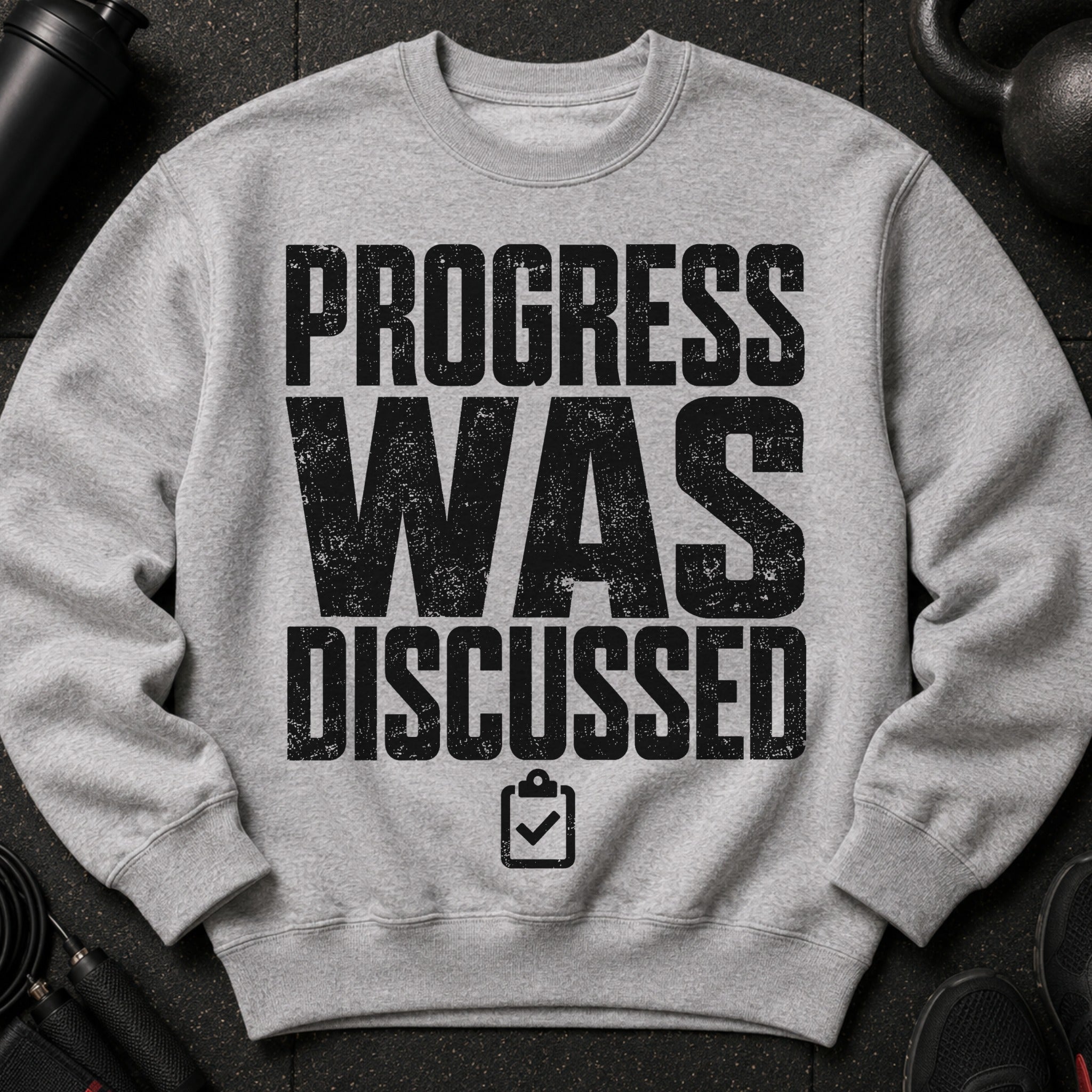 Grey sweatshirt with black distressed text "PROGRESS WAS DISCUSSED" and a checklist icon.