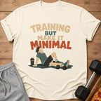 T-shirt graphic with text "TRAINING BUT MAKE IT MINIMAL" and resting figure.