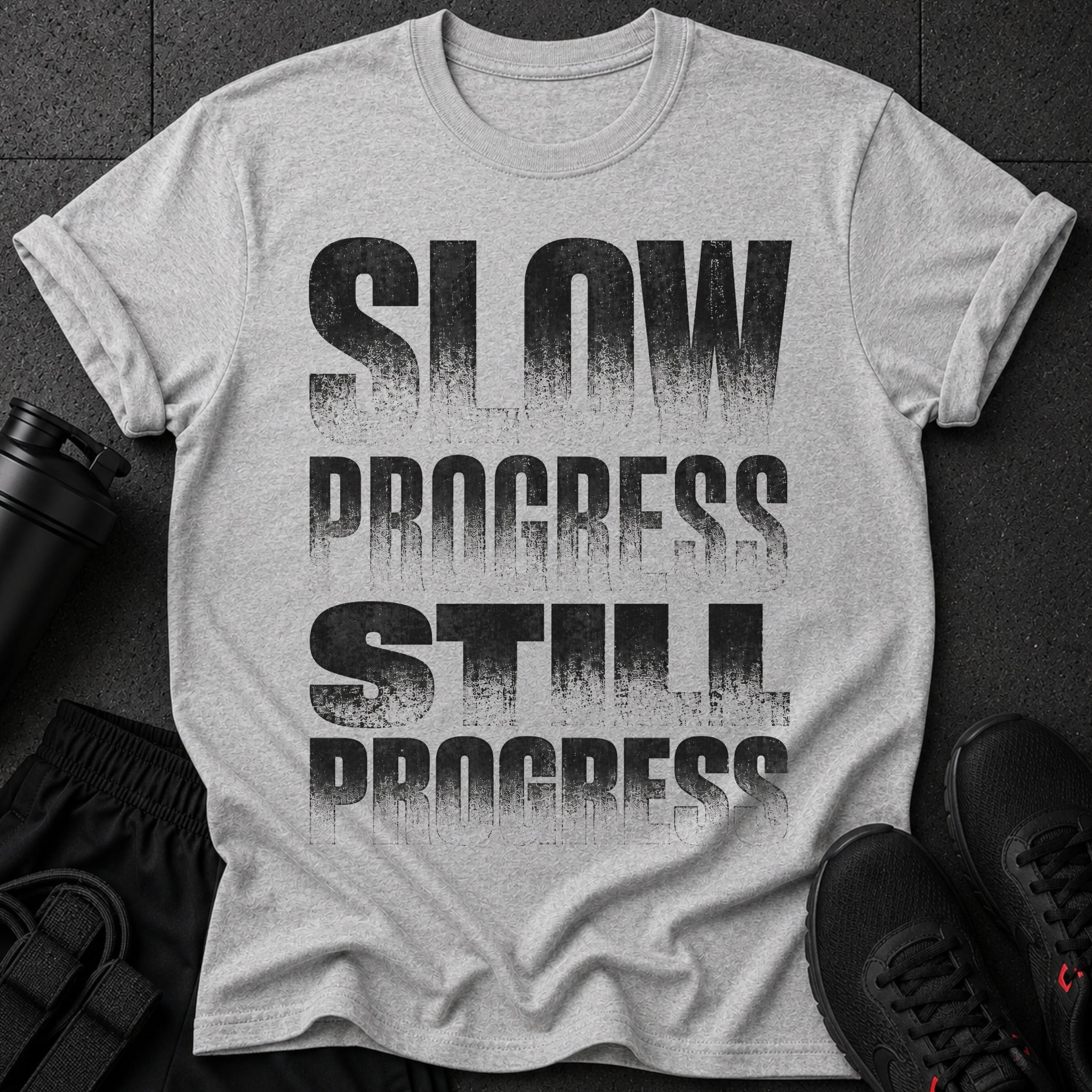 Gray t-shirt with "SLOW PROGRESS STILL PROGRESS" text in distressed black font.