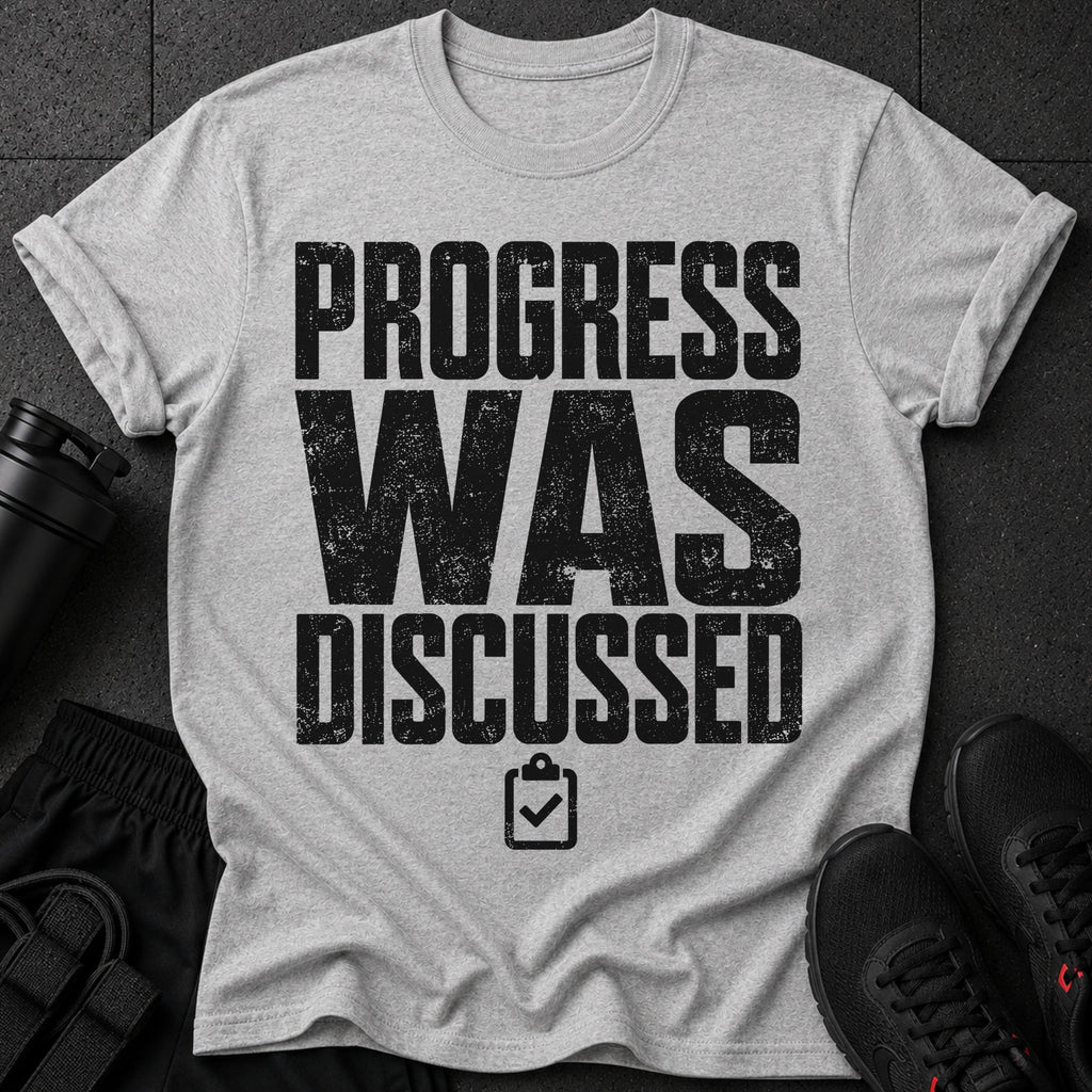 Grey t-shirt with black distressed text "PROGRESS WAS DISCUSSED" and a clipboard icon.