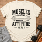 Cream t-shirt with "MUSCLES LOADING. ATTITUDE READY." text and barbell graphic.