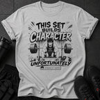 T-shirt with "This Set Builds Character Unfortunately" and a tired anime character lifting weights.