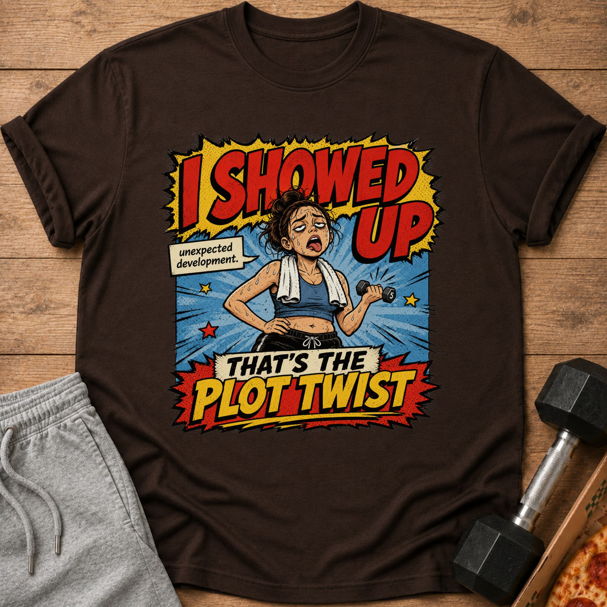 Brown t-shirt with a comic-style graphic of a tired woman lifting weights that says "I SHOWED UP".