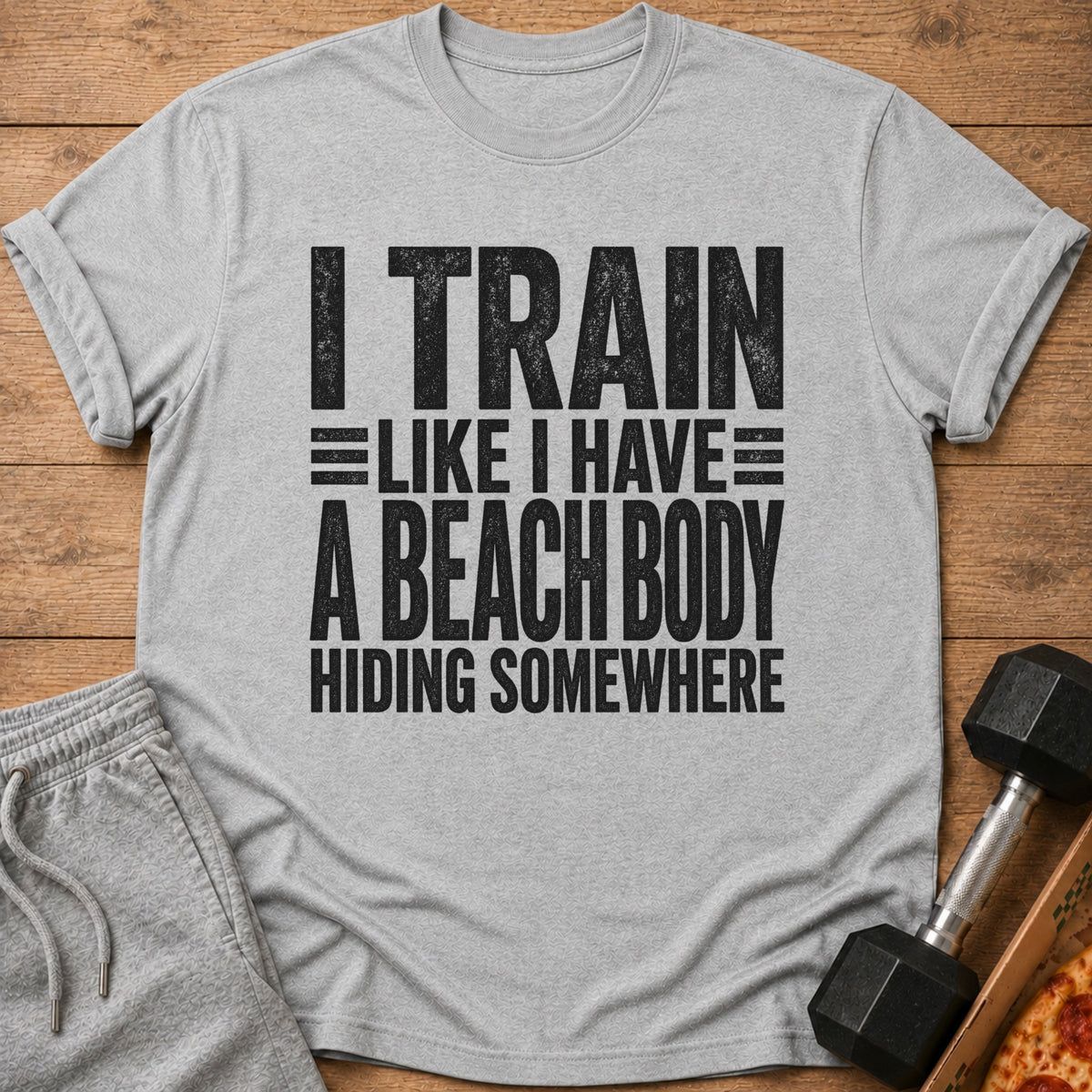 Grey t-shirt with black text "I TRAIN LIKE I HAVE A BEACH BODY HIDING SOMEWHERE".