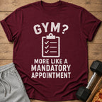 Maroon t-shirt with white text "GYM? MORE LIKE A MANDATORY APPOINTMENT."
