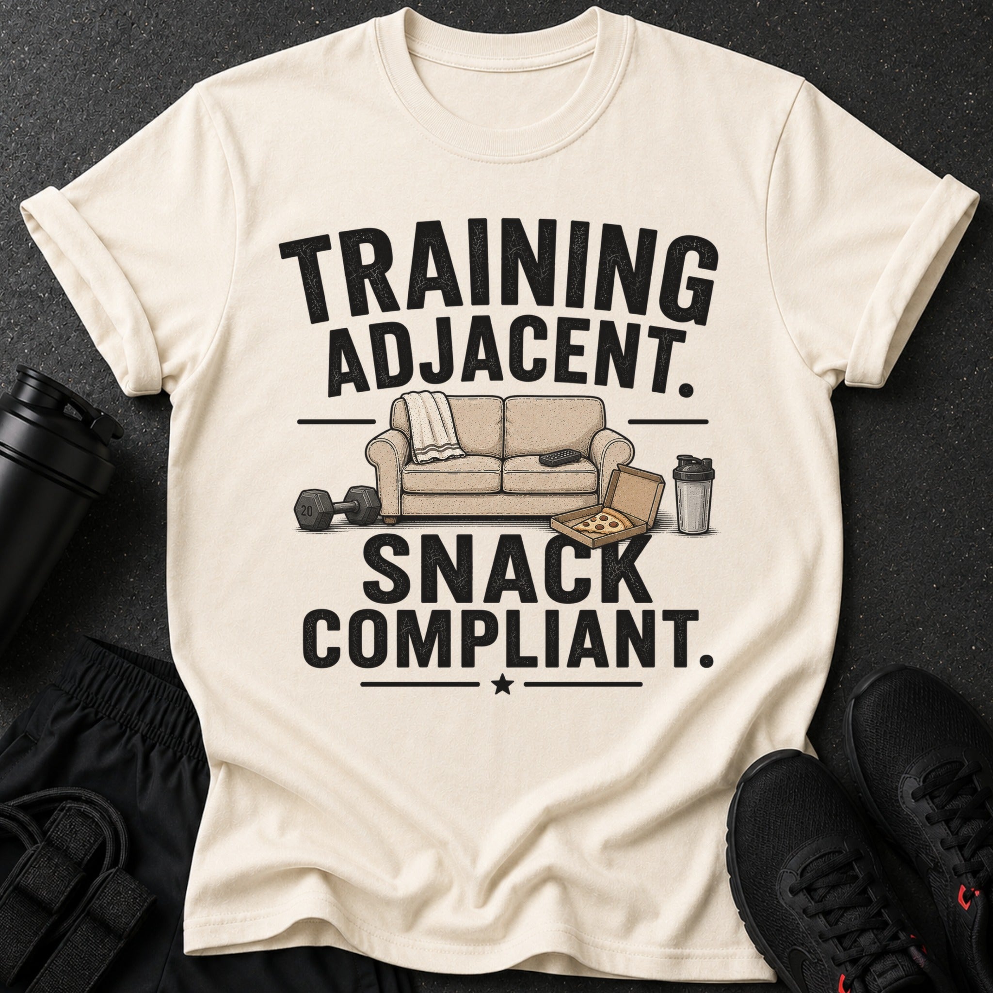 Cream t-shirt with black text "TRAINING ADJACENT. SNACK COMPLIANT." and graphics.