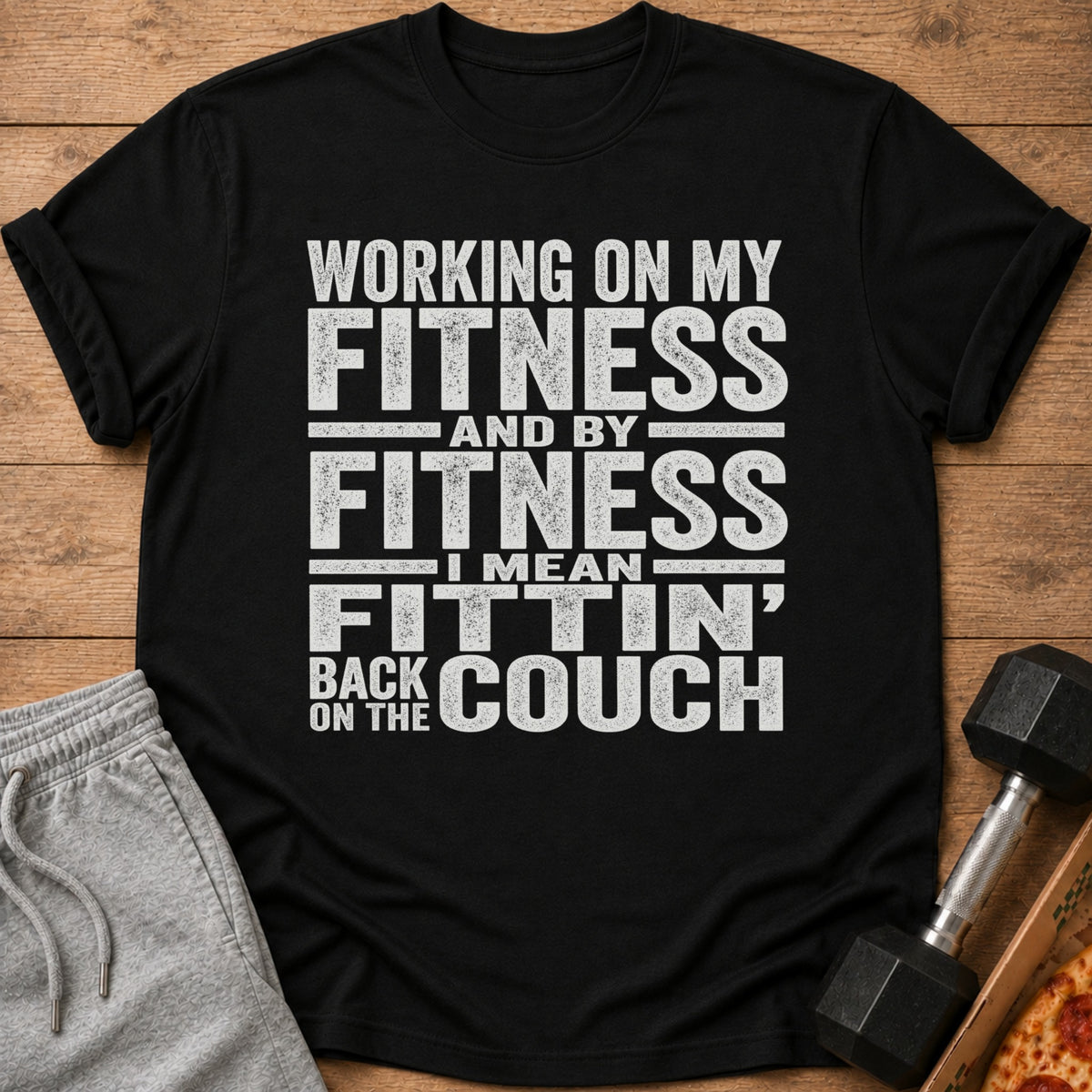 Black t-shirt with "Working on my fitness and by fitness I mean fittin' back on the couch" text.