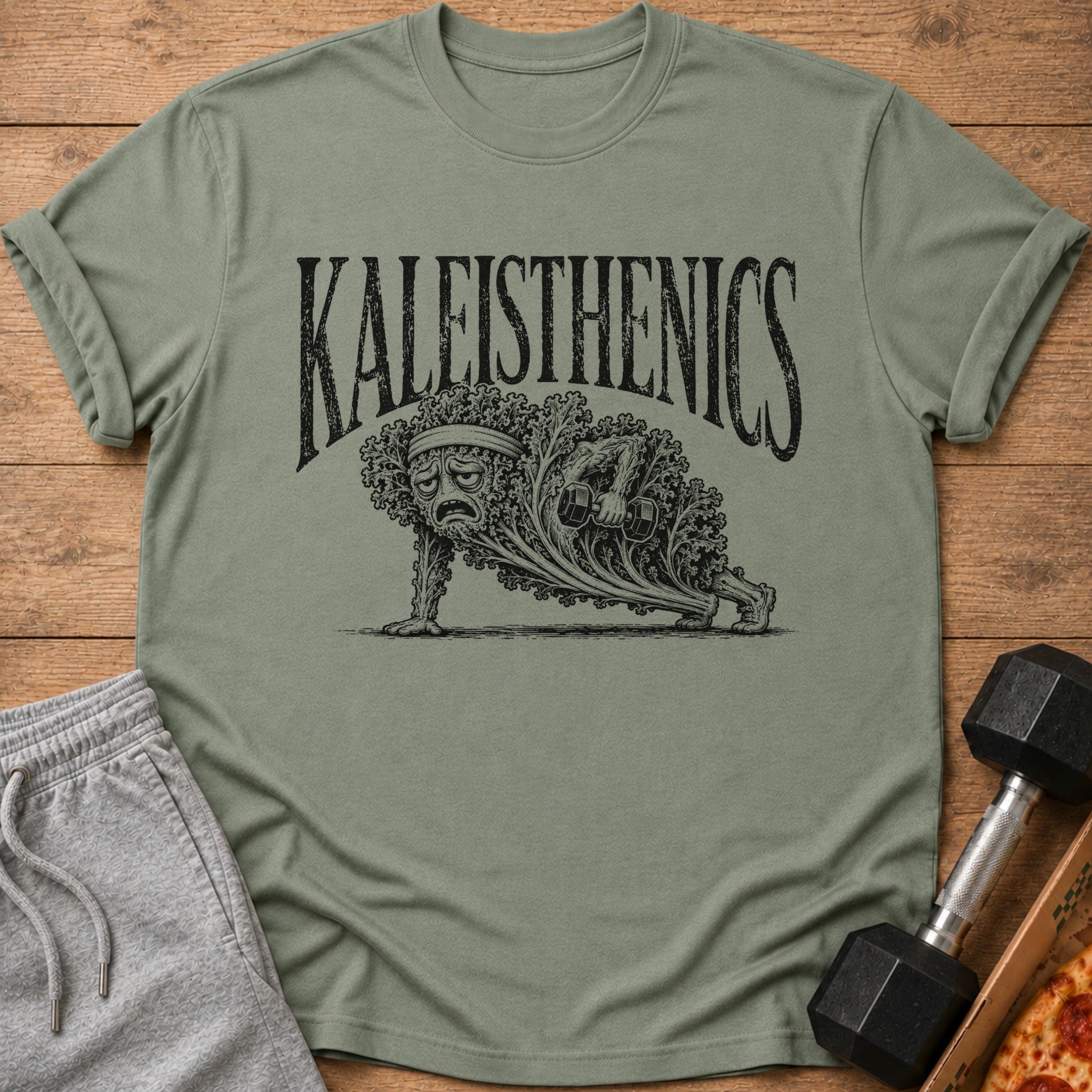 T-shirt with "Kaleisthenics" text and kale doing a plank with a dumbbell.