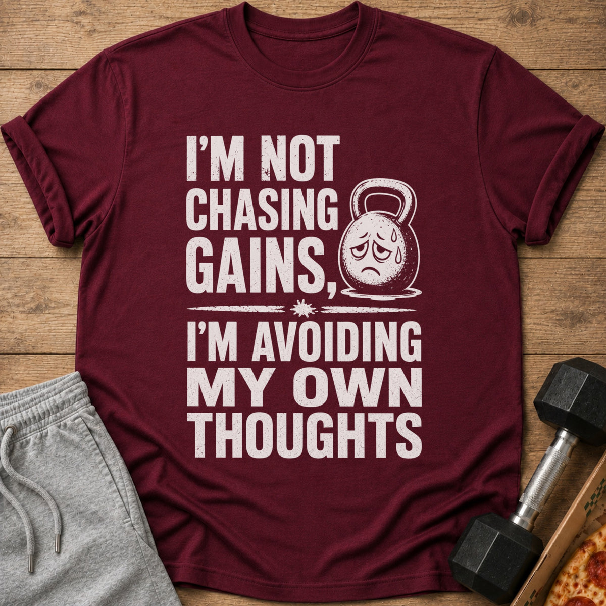 Maroon t-shirt with white text "I'M NOT CHASING GAINS, I'M AVOIDING MY OWN THOUGHTS".