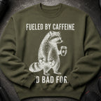 Green sweatshirt with raccoon lifting weights and holding coffee: "Fueled by Caffeine"