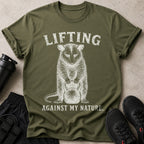Olive t-shirt with white graphic of a raccoon lifting a kettlebell and text.