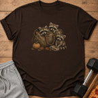 Three raccoons in a vintage duffel bag with pumpkin and leaves.
