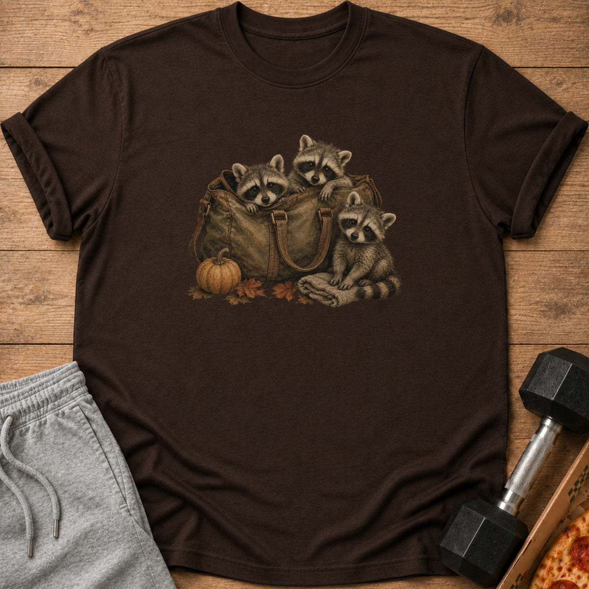 Three raccoons in a vintage duffel bag with pumpkin and leaves.