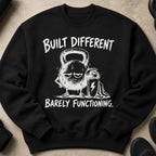 Black sweatshirt with a graphic of a tired kettlebell and shaker, stating "Built Different Barely Functioning."